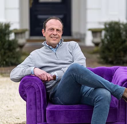 Jeroen Klerkx op een paarse bank voor het pand van Morgen Legal.